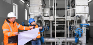 Zwei Bauarbeiter stehen mit einem Bauplan in der Hand und besprechen das weiter vorgehen der Bauarbeiten im Wasserwerk Grimma-Geithain.