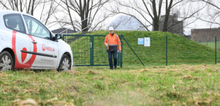 Ein Mitarbeiter von Veolia steht auf einer grünen Wiese. Im Hintergrund ist ein Firmenauto von Veolia zu sehen.