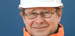Ein Bauarbeiter mit einer Brille und einem weißen Helm.